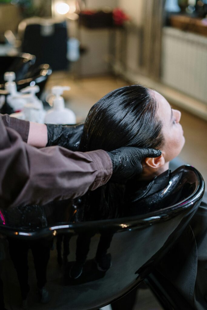 pexels-photo-3993451-3993451 A professional hairstylist washing a woman's hair in a modern salon setting, ensuring quality haircare.